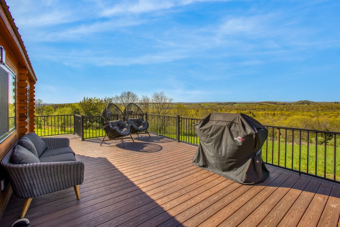 A wooden deck with outdoor seating and a grill.