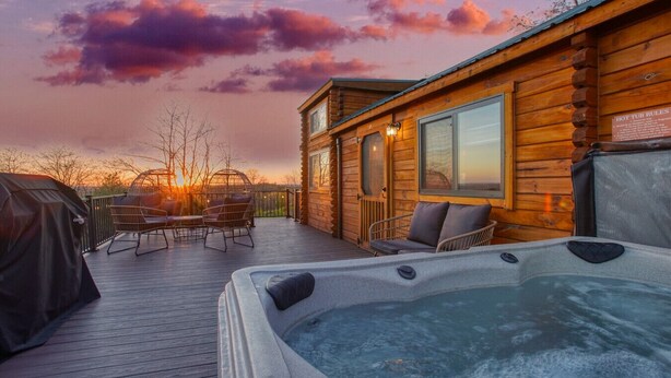 A wooden cabin with a hot tub and outdoor seating.