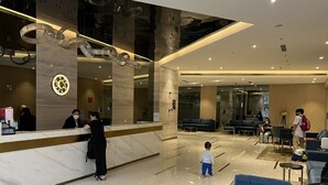 A spacious lobby with a reception desk, seating areas, and a child playing.