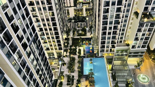 A high-rise building with multiple balconies, a central courtyard with a swimming pool, and a circular fountain.