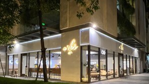 A modern building with a cafe on the ground floor, featuring large glass windows and a neon sign.