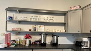 Una cocina con armarios grises, una cafetera, un hervidor y varios alimentos sobre la encimera.