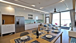 A modern kitchen with white cabinets, a built-in oven, and a dining area with a wooden table set for four.