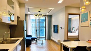 A modern kitchen with a built-in sink, a dining area with a table and chairs, and a large window offering a city view.