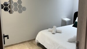 A modern hotel room with a neatly made bed, a small bedside table, and a wall-mounted mirror. - Ziad Studio Moderne (Casablanca)