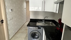 A compact kitchen with a washing machine, a sink, and a stove. - Ziad Studio Moderne (Casablanca)