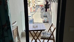 A view from a balcony with a table and chairs, a patterned curtain, and a street with parked cars and buildings in the background. - Ziad Studio Moderne (Casablanca)