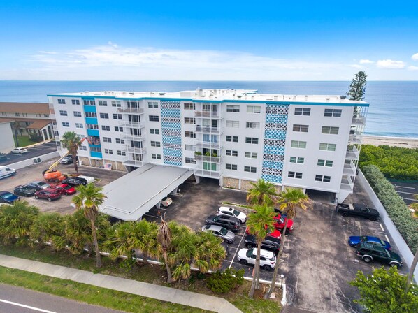 A multi-story hotel with a parking lot, a beach view, and a distinctive blue and white facade.