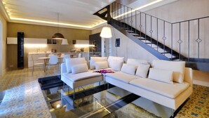 Un salon moderne avec un canapé, une table basse en verre et un escalier doté d’une rampe.