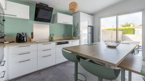 Eine moderne Küche mit weißen Schränken, einer Holzarbeitsplatte und einem Essbereich mit Tisch und Stühlen.