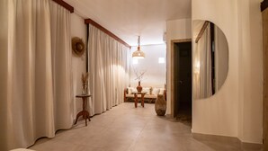 A room with a sofa, a round mirror, a table with a vase, and a hanging light fixture. - Casa Boutique de Playa  (Santa Marta)