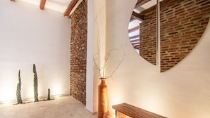 A room with a brick wall, a wooden bench, and a large vase with branches. - Casa Boutique de Playa  (Santa Marta)