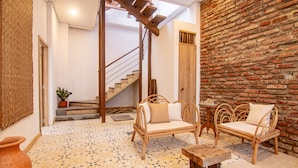A room with a brick wall, a staircase, wicker furniture, and patterned floor tiles. - Casa Boutique de Playa  (Santa Marta)