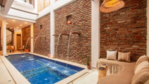 A swimming pool with a brick wall and a sofa with cushions. - Casa Boutique de Playa  (Santa Marta)