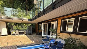 Een modern terras buiten met een blauw-wit geruit kleed, twee stoelen en een tafel.