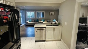 Een moderne keuken met een ingebouwde vaatwasser, een zwarte koelkast en een roestvrijstalen oven.