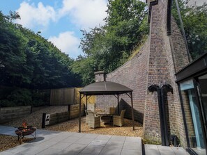 An outdoor patio with a brick barbecue area, seating, and a wooden fence. - The Tunnel at Bridge Lake Farm and Fishery (Banbury)