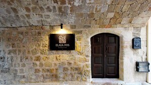 A stone building with a sign for "ELIA FOS Boutique Hotel" and a wooden door. - Elaia-Fos (Rhodes)