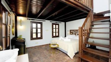 Une chambre à coucher avec un lit, une table de chevet, une petite table avec un verre et un escalier en bois.