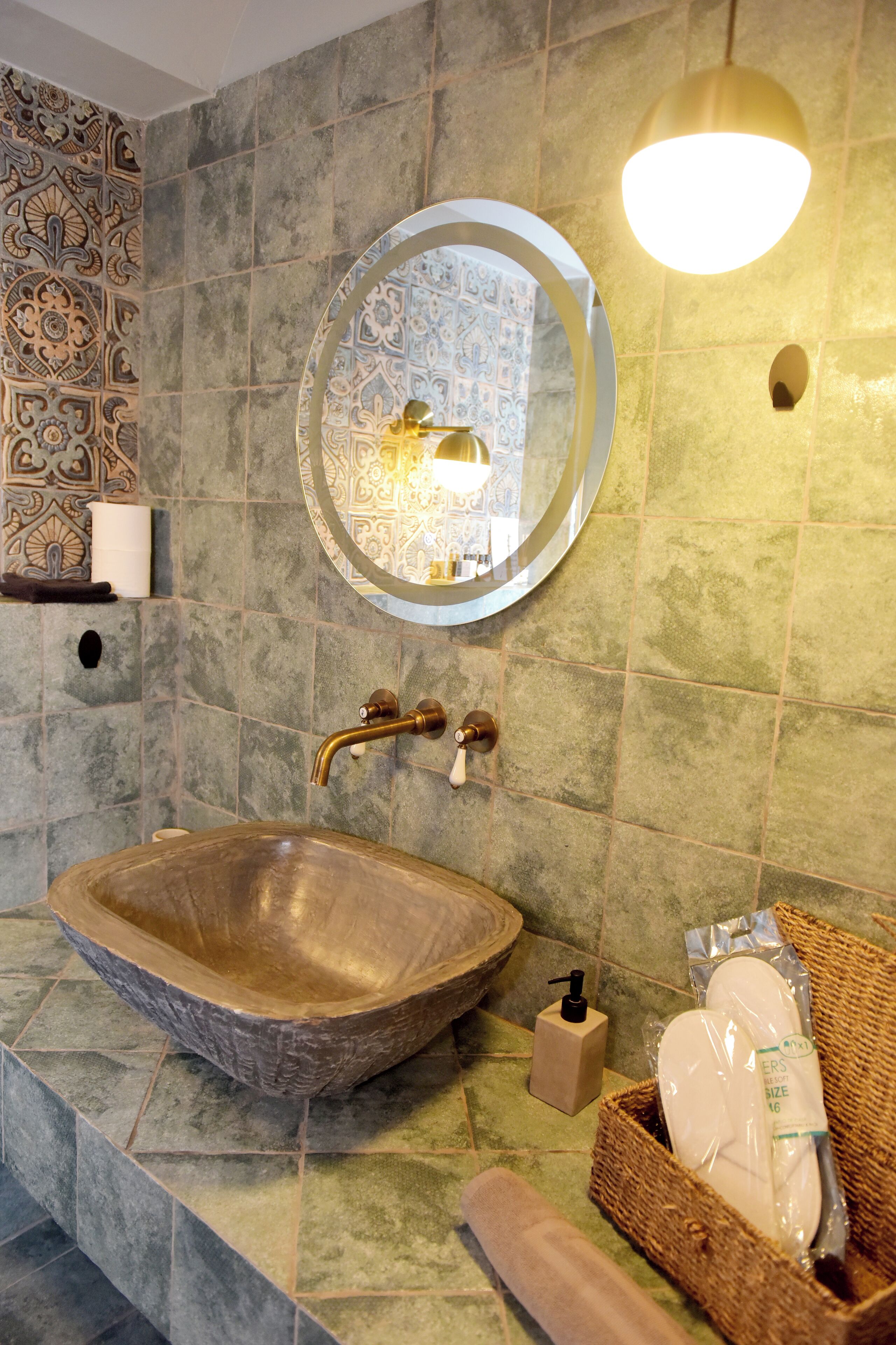 A bathroom with a large, round, wooden sink, a wall-mounted mirror, and a light fixture above the mirror.