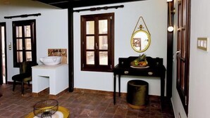 A room with a white sink, a wooden door, a mirror, and a small table with fruits. - Elaia-Fos (Rhodes)