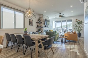 Amplia sala de estar con una mesa de comedor de madera, sillas negras, un sofá verde y un sillón amarillo.