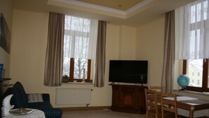 Una sala de estar con televisor, una mesa de comedor con sillas, un sofá y un globo terráqueo sobre la mesa.