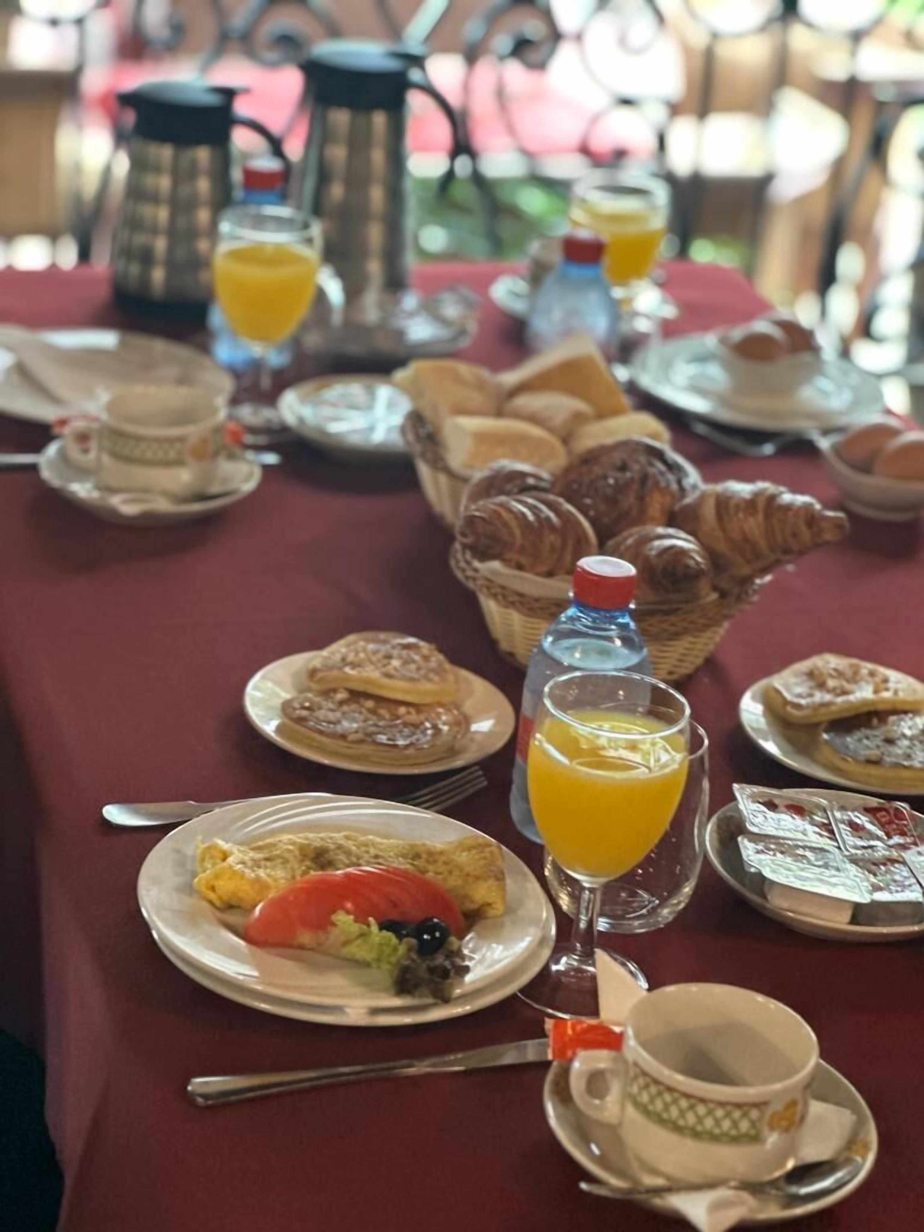 Un desayuno con platos de comida, cruasanes y jugo de naranja.