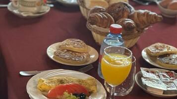 Un desayuno con platos de comida, cruasanes y jugo de naranja.