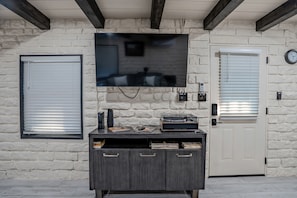 A stone wall with a flat-screen TV mounted above a dark wooden cabinet with drawers.