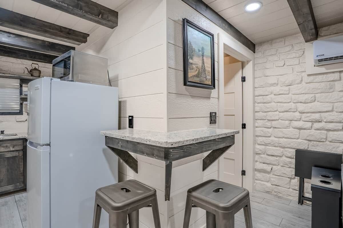 A kitchen with a white refrigerator, a microwave, a sink, and a bar area with stools.