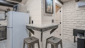 A kitchen with a white refrigerator, a microwave, a sink, and a bar area with stools.