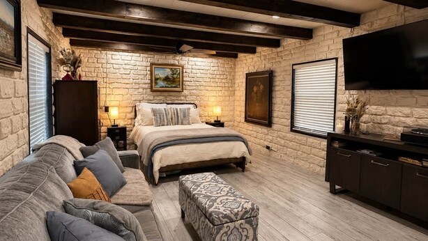 A bedroom with a bed, a sofa, a TV, and a fireplace.