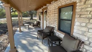 A covered patio area with stone walls, outdoor furniture, and a window.
