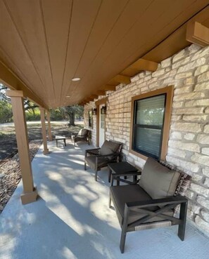 A covered patio area with stone walls, outdoor furniture, and a window.