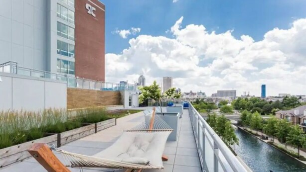 Una hamaca en una terraza en la azotea con vistas a la ciudad, un río y un edificio de fachada roja.
