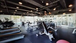 Un gimnasio con cintas de correr, máquinas de pesas y pesas libres.