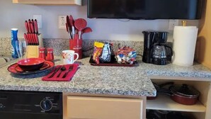 Una cocina con encimeras de granito, cafetera, microondas y diversos utensilios.