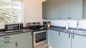 A modern kitchen with a built-in microwave, stove, oven, and a large window. - Courtyard Casita - 2bed/2bath Inn (Torrey)
