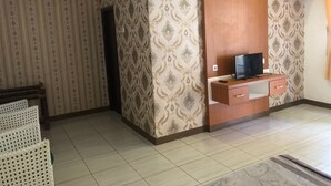 Una sala con papel tapiz estampado, un mueble de madera para entretenimiento y un televisor de pantalla plana.