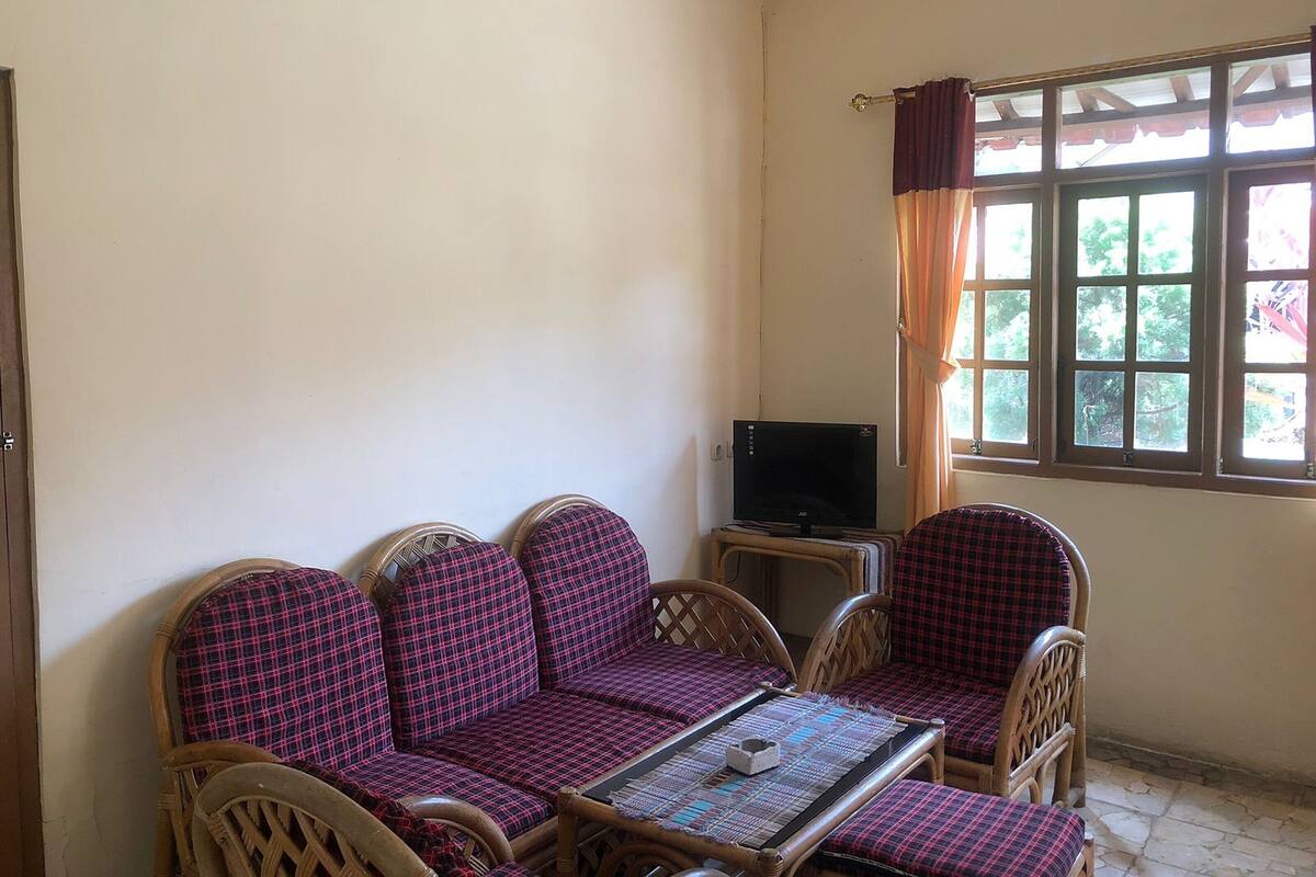 A room with a sofa set, a television, and a window with curtains.