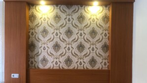 Un dormitorio con cabecera de madera, dos mesitas de noche y un papel tapiz estampado.