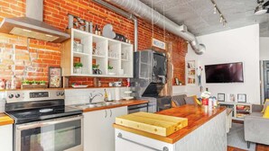 Een moderne keuken met een bakstenen muur, roestvrijstalen apparatuur en een houten kookeiland.