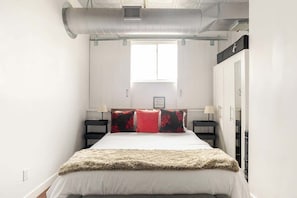 Un dormitorio con una cama, dos mesitas de noche, un armario y una ventana.