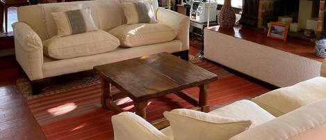 Un salon avec un canapé, une table basse et un téléviseur. Il y a une cheminée et une plante.