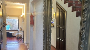 Un pasillo con un espejo grande y ornamentado que refleja una escalera y una puerta.