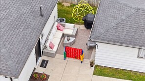 A residential backyard with a covered patio, a yellow play structure, and a welcome mat. - King Bed, Fenced Yard, Parking, TV’s in all rooms! Near parks  (Fort Wayne)