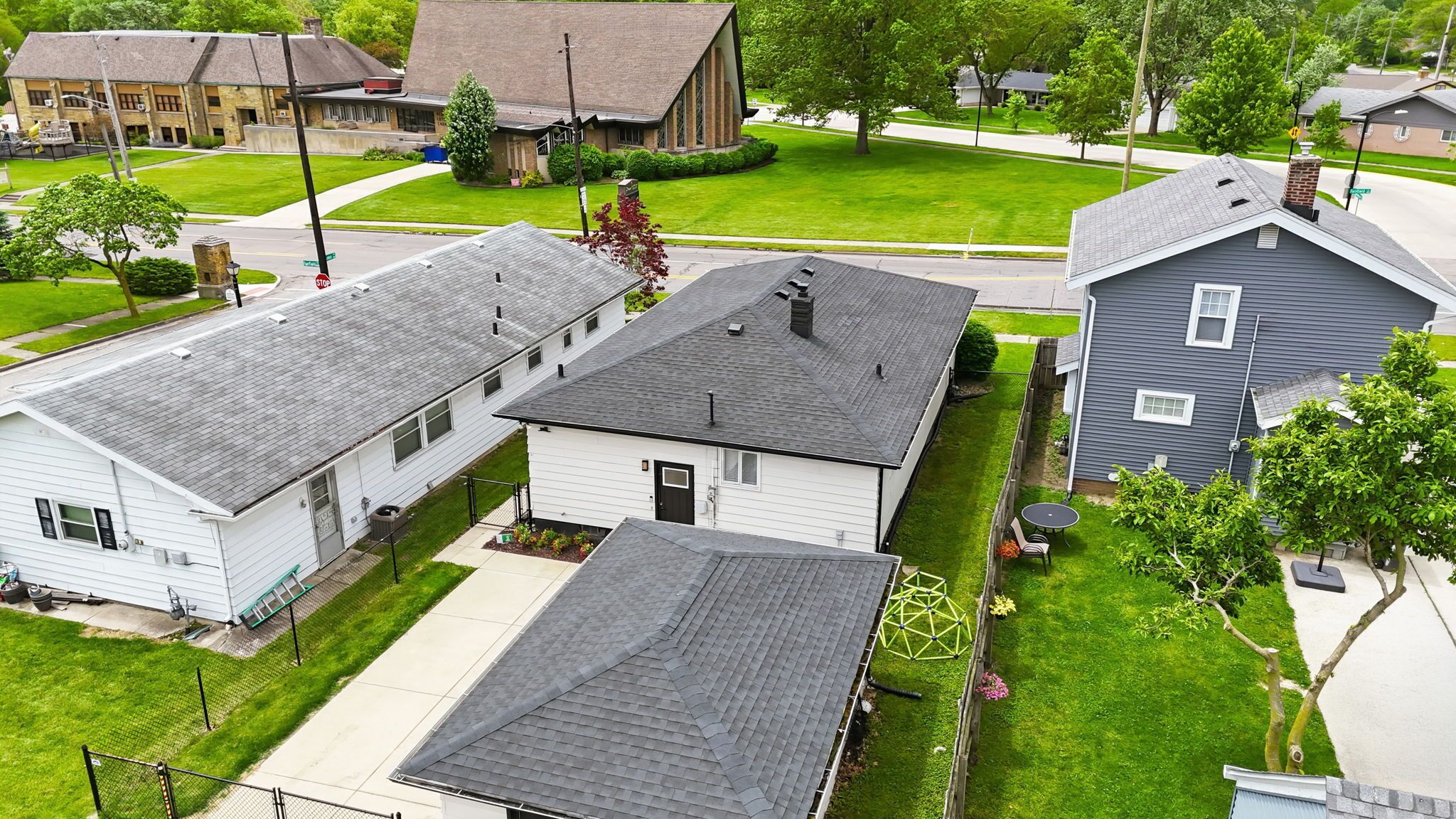 A residential area with houses, a stop sign, and a clear sky.