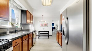 A modern kitchen with wooden cabinets, stainless steel appliances, and a central island. - King Bed, Fenced Yard, Parking, TV’s in all rooms! Near parks  (Fort Wayne)