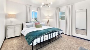 A bedroom with a bed, bedside tables, a lamp, a mirror, and a view of the outside. - King Bed, Fenced Yard, Parking, TV’s in all rooms! Near parks  (Fort Wayne)